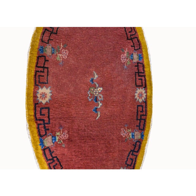 An unusual early 20th century oval Chinese Art Deco rug with a cranberry center, surrounded by a meandering motif and...