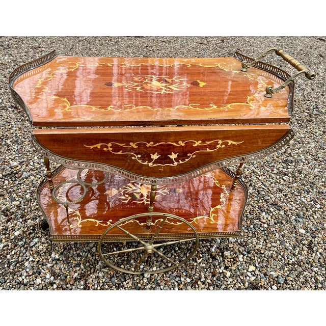 A splendid, two tier rolling bar cart in the Hollywood Regency style. Italian marquetry inlaid design with high gloss...
