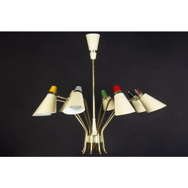 Singular iconic stilnovo chandelier, features eight rotating arms, each supporting the ivory lacquered and multicolored,...