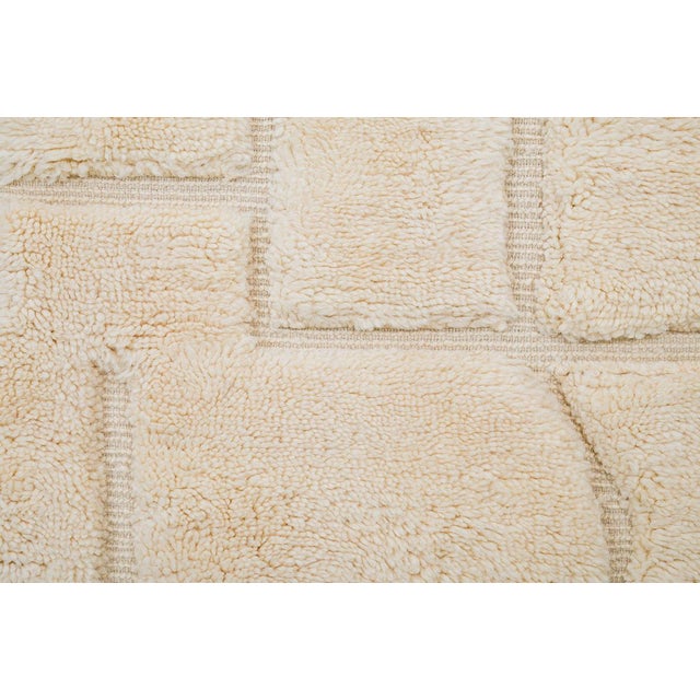 Sophisticated hand-knotted wool rug showcasing a linear design of soft geometric shapes in warm Ivory tones. Its plush...