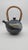 A sculptural studio pottery teapot featuring a rounded body, expressive cobalt and cream drip glaze, and a woven bentwood...