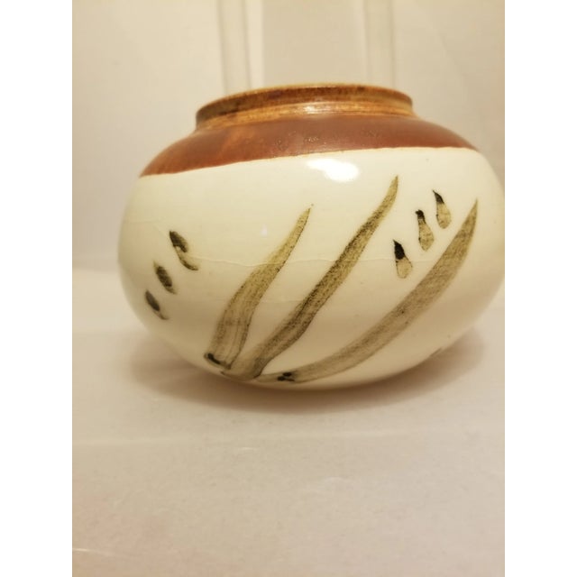 This is a vintage ADK studio pottery vase. Initialed by the artist, the hand-crafted vase features a glaze on the base...