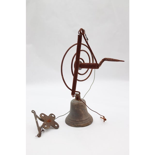 This antique doorbell mechanism works with a pull string attached to a door, which would pull the wire to ring the bell....