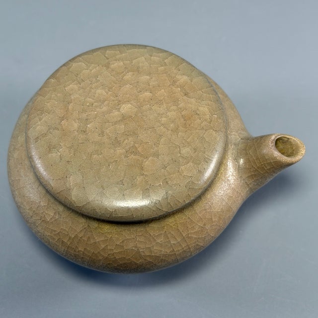 Fine antique Chinese celadon lidded ewer. Rounded bulbous body fitted with short spout and matching cover, covered in rich...
