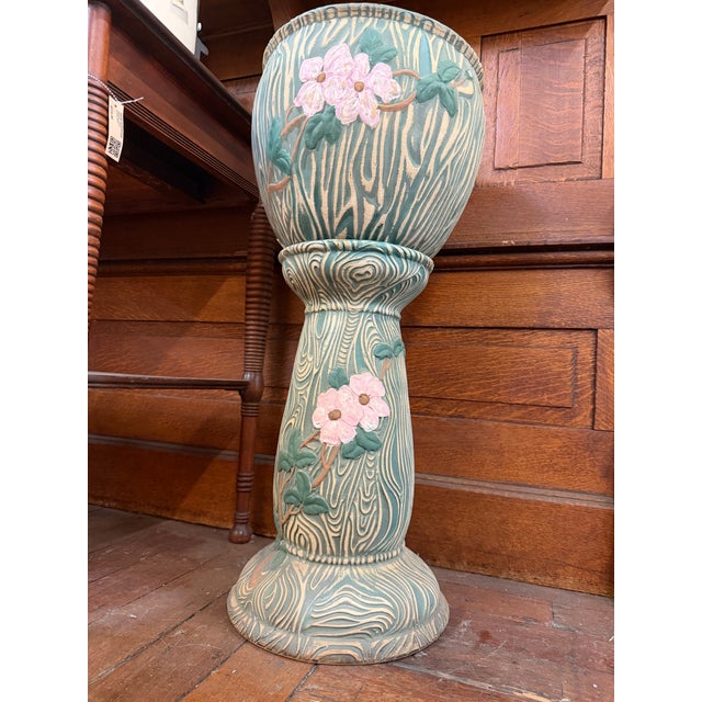 Decorative ceramic jardinière and pedestal featuring raised pink blossoms, green foliage, and a distinctive woodgrain-...