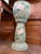 Decorative ceramic jardinière and pedestal featuring raised pink blossoms, green foliage, and a distinctive woodgrain-...