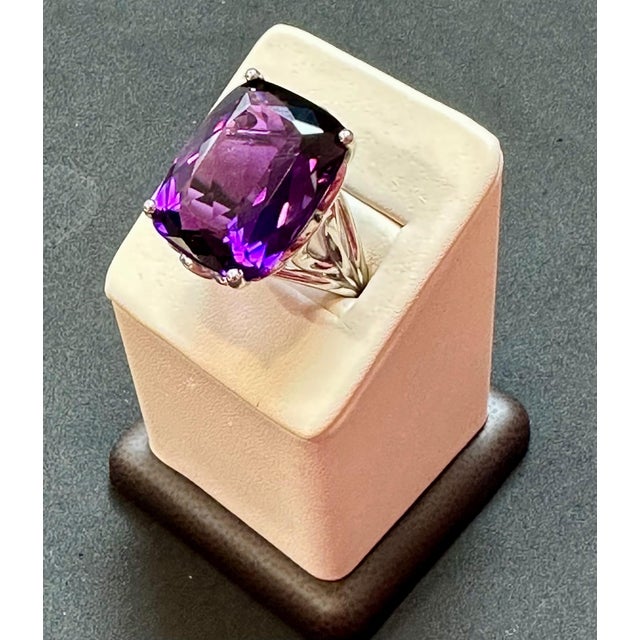 This vintage cocktail ring is a stunning piece of jewelry that features a huge 38 carat cushion-cut natural amethyst set...