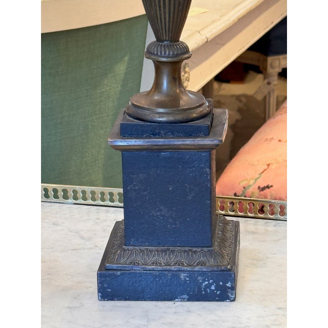 A handsome Neoclassical bouillotte lamp rising from a stepped plinth to a slender brass urn body with scrolled rosette-...