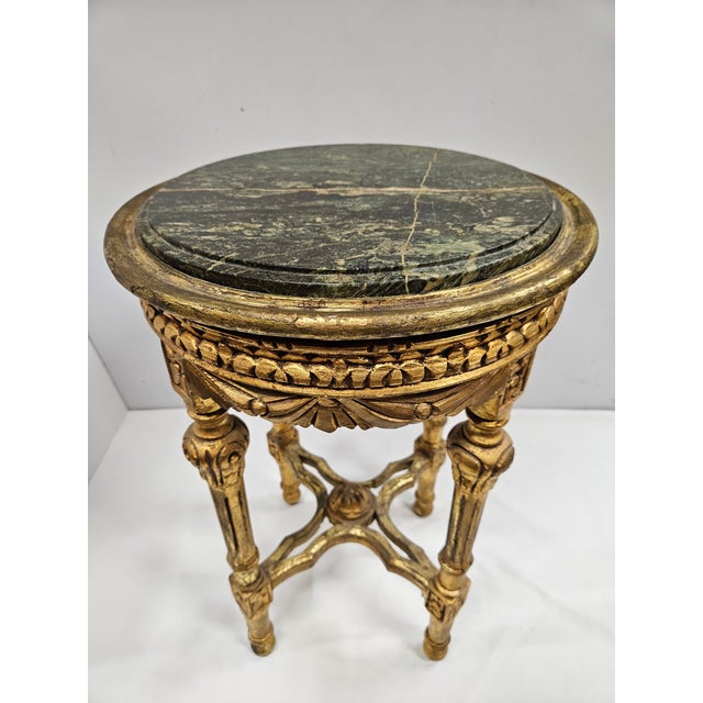 This antique round baroque side table features a gilded finish and a green marble top. The table has intricate carvings...