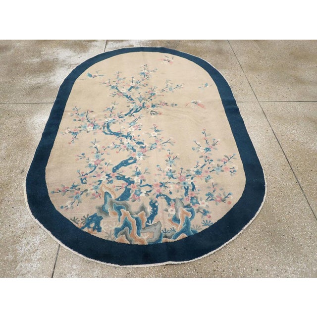 This mid-20th century Chinese Art Deco rug, features an elegant oval shape with a delicate and finely detailed floral...