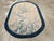 This mid-20th century Chinese Art Deco rug, features an elegant oval shape with a delicate and finely detailed floral...