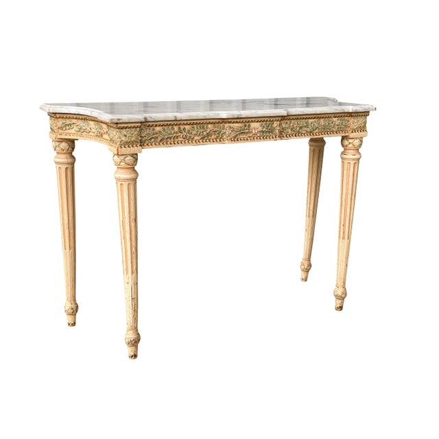 Shaped rectangular white and grey marble top over a conforming frieze carved with green painted laurel leaves and raised...