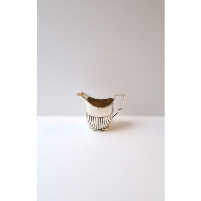 An English sterling silver coffee creamer, Edwardian Neoclassical design, crafted by the respected English silversmiths...