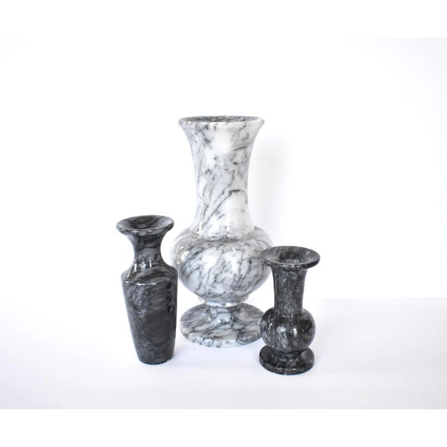 A set of three vintage carved stone marble vases, in classic baluster shapes in light gray and dark gray with mottled...