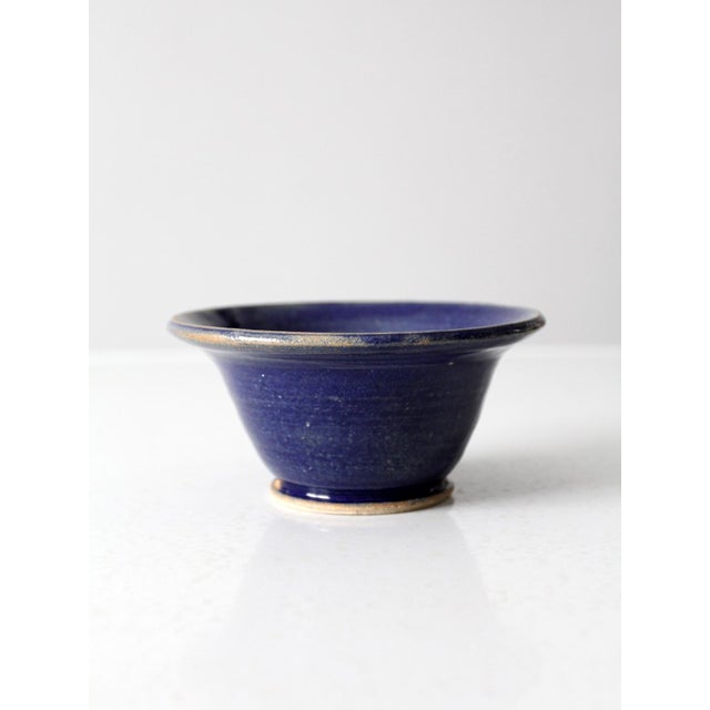 This vintage handmade studio pottery bowl features a deep blue glaze with natural tonal variation across the surface,...