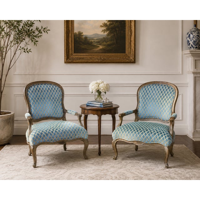 These vintage French Provincial Louis XV–style armchairs have carved giltwood frames, cabriole legs, and a low, wide...