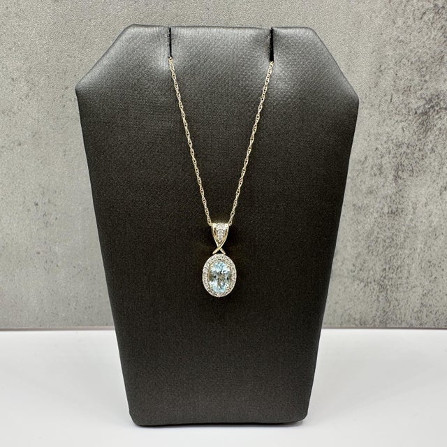 This aquamarine and diamond pendant necklace is crafted in 10kt yellow gold and features a beautiful 6.9 x 4.9mm oval cut...