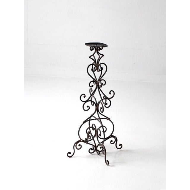 This vintage iron candle stand features an elegant open scrollwork design and a tall, sculptural silhouette that makes a...