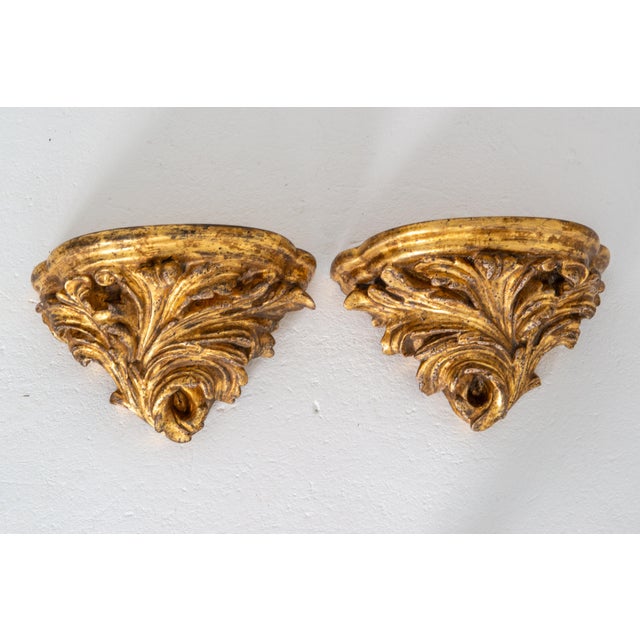 A pair of 1920s water gilt foliate carved wall brackets with a curved flat shelf which is 8.5" deep. In the Baroque style....