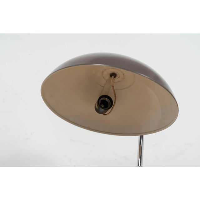 Model 144 desk lamp by H. Busquet for Hala Zeist. The light comes with a brown coated metal shade and base. The frame is...