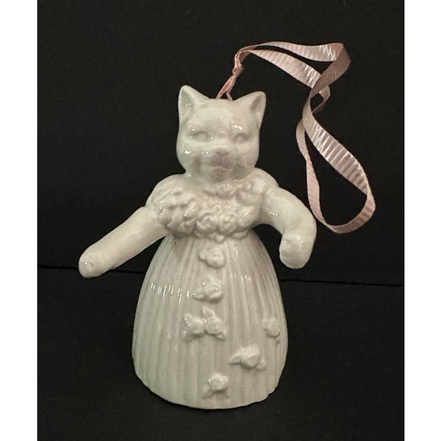White cat shaped bell wearing a floral dress and ballerina slippers. Pink ribbon for hanging. Measures approximately 2” x...