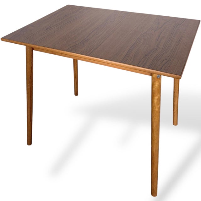 A classic mid-century square dining table produced in Czechoslovakia, featuring a rich Formica top paired with solid wood...