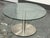 Design Plus Gallery presents the Berta Coffee Table by Scandinavian Design. A round glass top rests on a cylindrical metal...