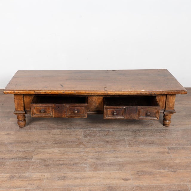 19th-century French oak coffee table featuring a deep, richly aged patina resting on four turned legs. The simple form...