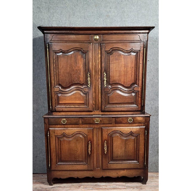 A louis xv period two-part oak buffet, circa 1750. The front opens with four doors and three drawers, mounted in gilt...