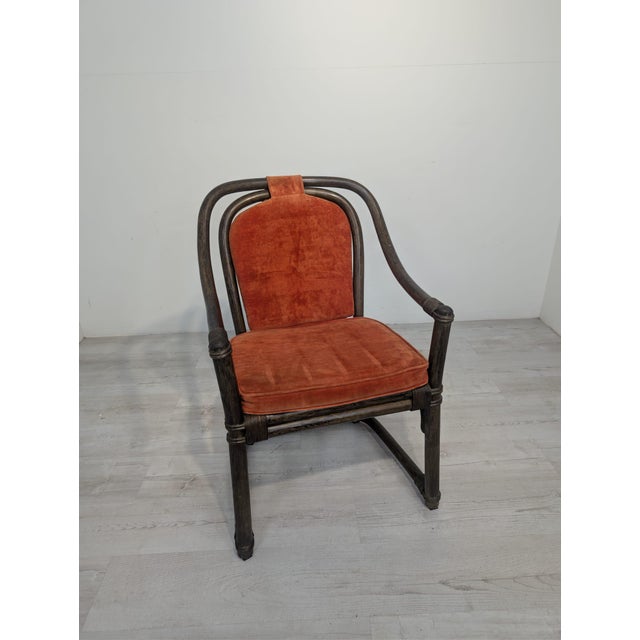 This armchair is made of rattan and features distinctive vintage armrests. The seat and backrest are upholstered in soft,...