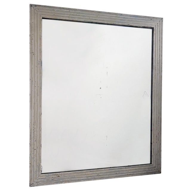 This large wall mirror with a reeded frame was made in France in the early 19th century. The frame has a reeded design...