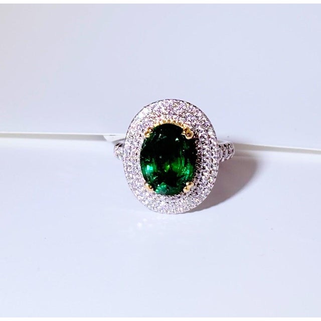An exceptional 18K white and yellow gold halo ring featuring a GIA-certified natural Zambian oval emerald weighing 3.65...