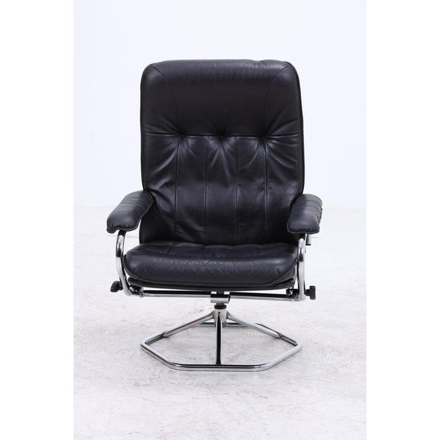 Vintage leather armchair by Unico with matching ottoman and chrome base. The armchair swivels and its reclining position...