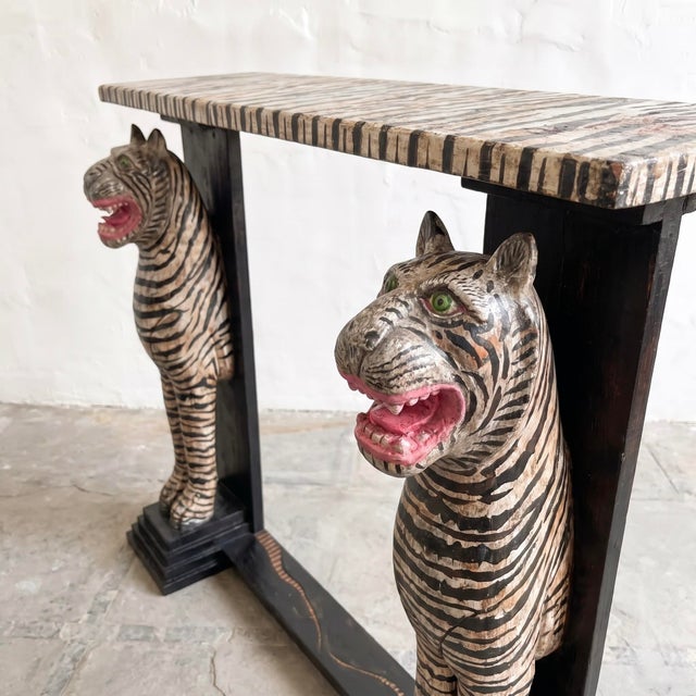 A distinctive vintage wooden console table with hand-painted tiger stripes and sculptural tiger figures forming the...