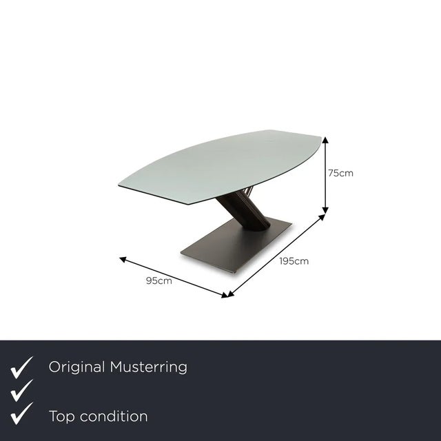 The dining table from Musterring consists of a glass top and stands on a stylish base. It is characterized by its elegant...