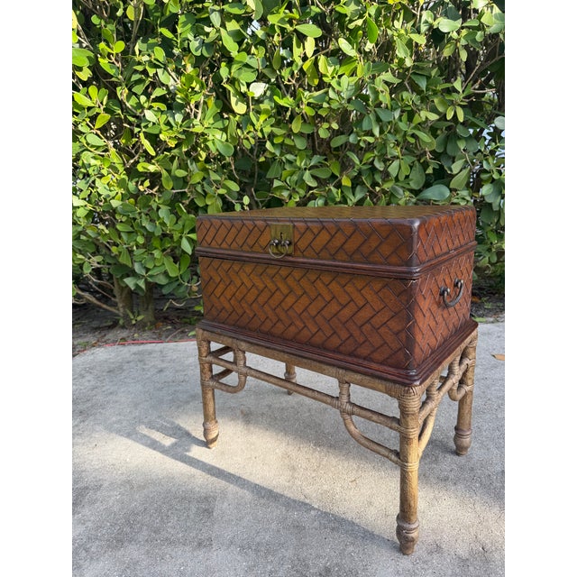 Leather wrapped storage chest on a faux bamboo stand with brass campaign-style hardware and a removable lift-off lid. The...