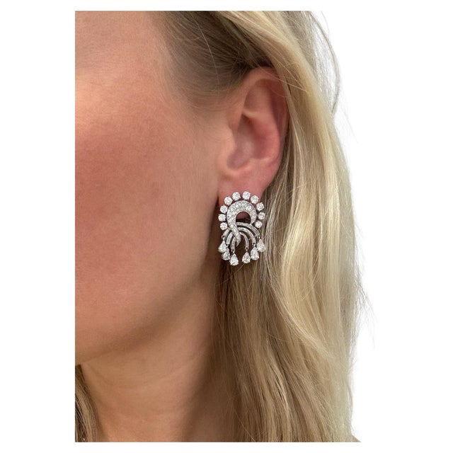 These beautifully crafted earrings in a swirling spray design containing 104 round brilliant, baguette and pear shaped...