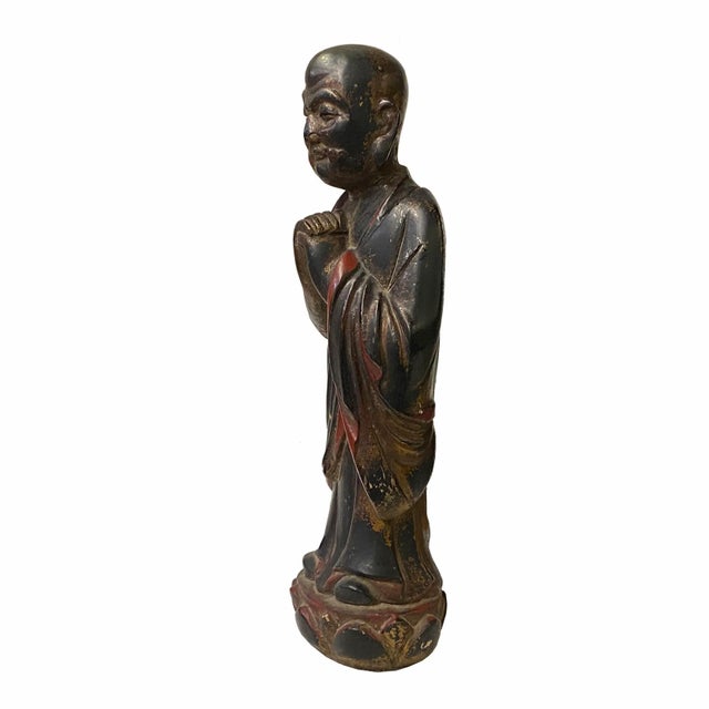 This is a decorative Chinese monk logon figure made of wood and painted with distressed black brown lacquer red accent...
