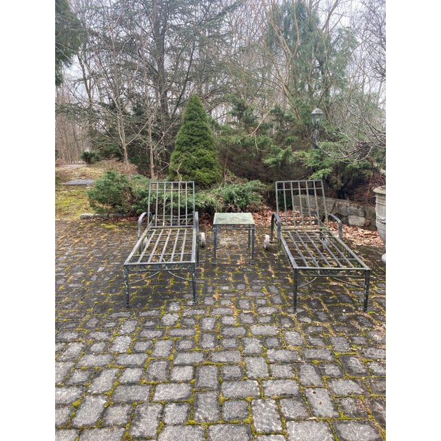 Pair of outdoor cast aluminum chaises with back wheels for easy moving.