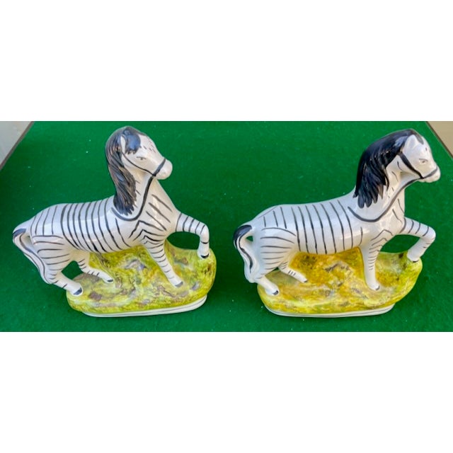 A Pair of English Staffordshire glazed porcelain animalier figures. each raised on naturalistic bases. Circa 1850-1870.