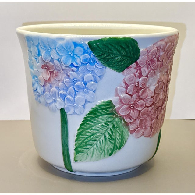 Hand‑painted Italian ceramic planter featuring richly sculpted hydrangea blooms in vibrant pinks and blues. The raised...