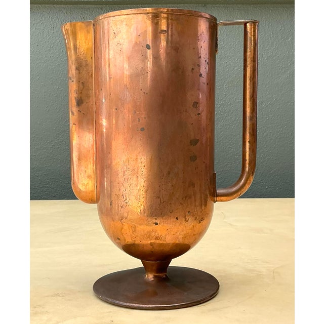 Capture the essence of mid-century industrial elegance with this striking Art Deco copper pitcher. Featuring a...