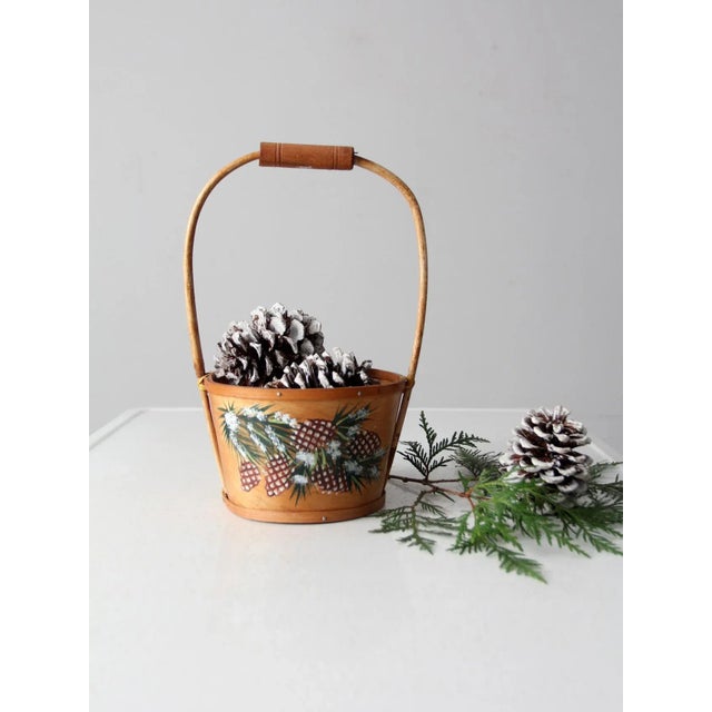 Experience the warmth of vintage with this beautiful balsa wood basket. Hand-painted winter pinecones give it a special...