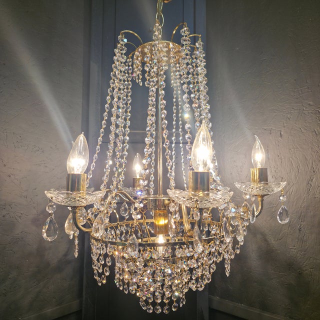 A glamorous vintage gold brass plated and chrome and crystal wedding cake chandelier, featuring a waterfall design of...