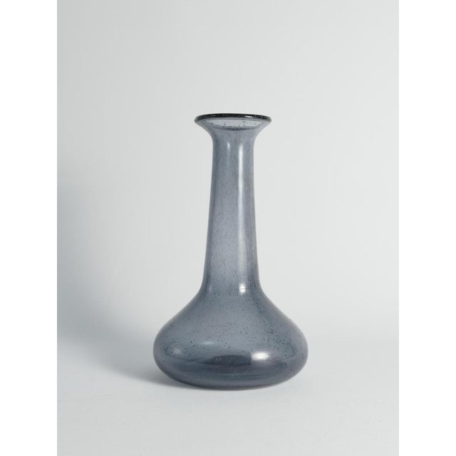 Dive into the understated charm of this mesmerizing blue glass vase crafted by the skilled hands of artist erik höglund...