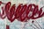 A heavy, looping band of crimson crosses a cool ground of pale blue and cream, layered with collage elements, fine drawn...