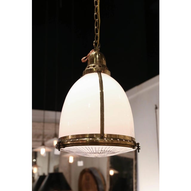 An antique pendant fixture of white and clear etched glass, banded and capped with brass and suspended on a 48" long chain...