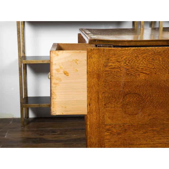 An English oak draper's table from the 19th century, with brass measuring tape and drop leaves. Created in England during...