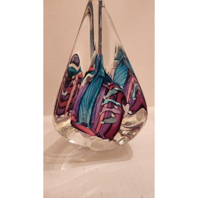 This listing features an abstract tear drop shaped glass sculpture with purple, pink, and blue abstract glass pieces...