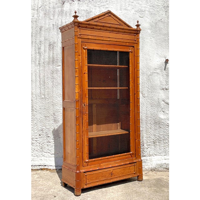 Embrace the allure of coastal elegance with this exquisite vintage armoire. The faux bamboo detailing and wire front evoke...